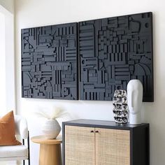 a living room with two black art pieces on the wall