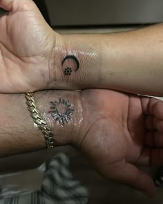 two people with matching tattoos on their arms, one holding the other's hand