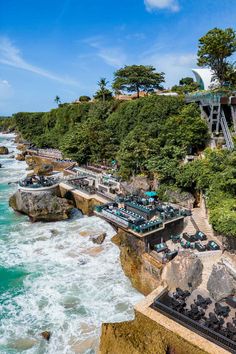 an aerial view of the ocean and beach with many tables set up on the rocks