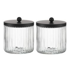 two glass jars with black lids are sitting next to each other on a white background