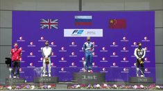 three men standing on top of a podium in front of a blue screen with flags