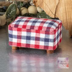 a red, white and blue checkered footstool sitting next to a christmas tree