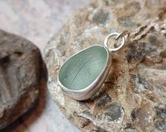 a green sea glass pendant sitting on top of a rock