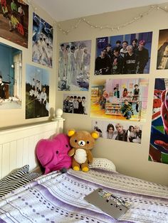 a bedroom with posters on the wall and a teddy bear sitting on the bed in front of it