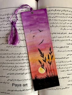 an open book with a painting on it and a tassel hanging from the cover