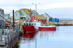 two boats are docked in the water next to some colorful houses and piers on an overcast day