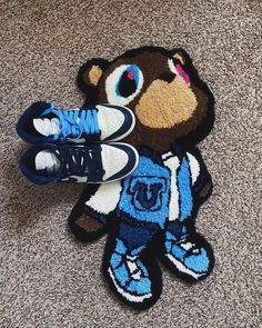 a pair of sneakers is sitting on the floor next to a rug with an image of a teddy bear