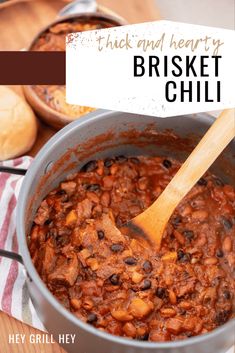 a pot full of chili and beans with a wooden spoon in it on a table