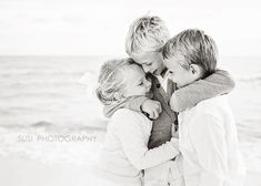 three children hugging each other on the beach