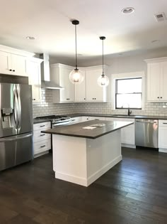 a large kitchen with white cabinets and stainless steel appliances, along with hardwood flooring