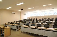 an empty classroom with rows of desks and chairs in front of the windows,