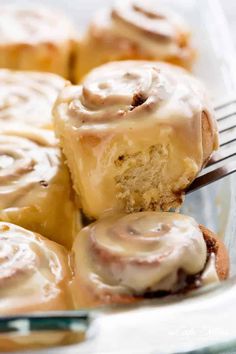 cinnamon rolls with icing sitting on top of a white plate