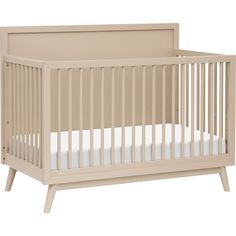 a baby crib with white sheets on the bottom, and no mattress in it