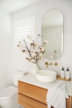 a white bathroom with flowers in a vase on the counter and an instagram message