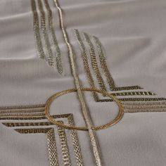 a close up view of an embroidered fabric with gold and silver lines on it's edges