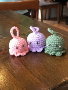 three small crocheted animals sitting on top of a wooden table