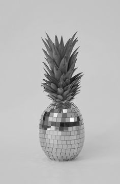 a pineapple sitting on top of a disco ball in front of a gray background