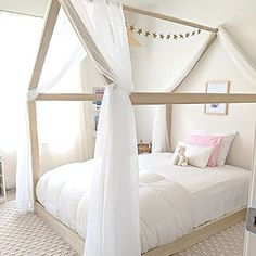 a bed with white sheets and curtains in a room