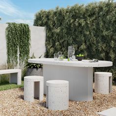 an outdoor dining table with four stools in the middle of graveled area next to shrubbery