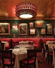 a dining room with red booths and paintings on the wall above it's tables