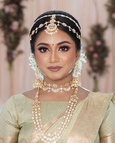 a woman wearing a gold and white bridal outfit with pearls on her necklace, earrings and headpiece