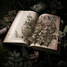 an open book sitting on top of a lush green field next to flowers and plants