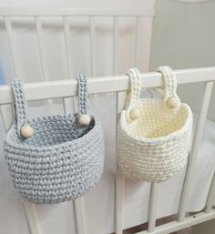 two crocheted baskets hanging from the side of a crib, one with handles