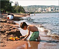 a young boy playing in the sand at the beach