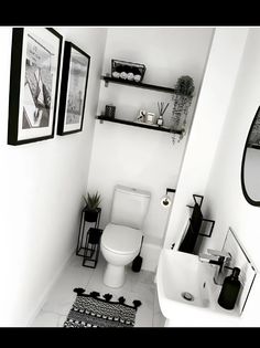 black and white bathroom with pictures on the wall above the toilet, sink and mirror