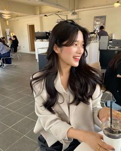 a woman sitting at a table with a drink in her hand