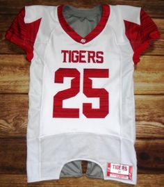 a white and red football jersey with the number twenty five on it sitting on top of a wooden floor