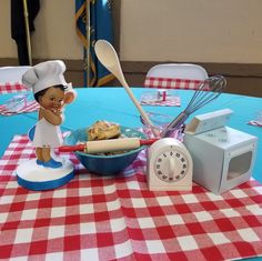 a table topped with a blue and red checkered tablecloth covered table cloth next to a toy chef