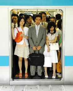 a group of people standing on a subway train with the doors open and one person holding a briefcase