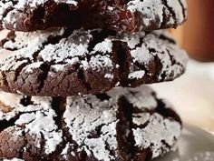 three chocolate crinkle cookies stacked on top of each other with powdered sugar