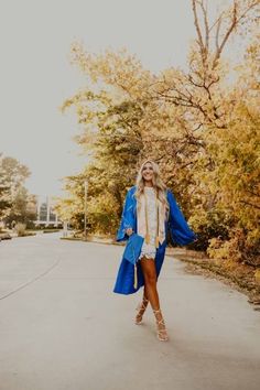 a woman in a blue coat is walking down the street