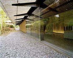 an empty walkway in front of a building with lots of glass on the side and trees behind it