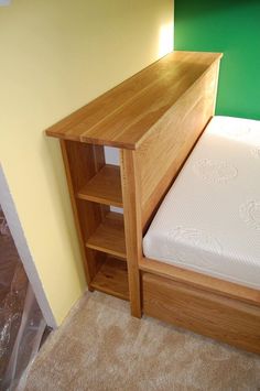 a bed with a wooden headboard next to a green wall and white carpeted floor