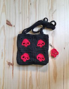 a crocheted bag with red skulls on it and a keychain attached