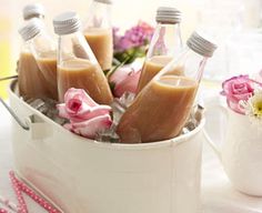 several bottles filled with liquid sitting on top of a white table next to pink flowers