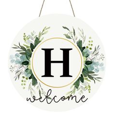 a welcome sign hanging from a rope with the letter h on it's side