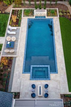 an aerial view of a swimming pool surrounded by lawn furniture and landscaping area with grass