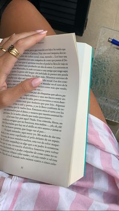 a woman is reading a book while laying on her stomach and holding it in her hand