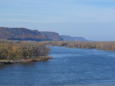 a body of water surrounded by trees in the middle of fall time with mountains in the background