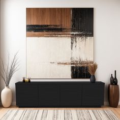 an abstract painting hangs on the wall next to a black and white cabinet with vases