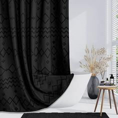 a black and white bathroom with a bathtub, shower curtain and rug on the floor