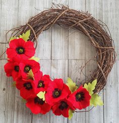 a wreath with red flowers and green leaves on a wooden surface, ready to be used as an ornament