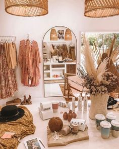 a table topped with lots of items next to a wall mounted mirror and lights hanging from the ceiling