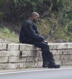 a man sitting on the edge of a stone wall