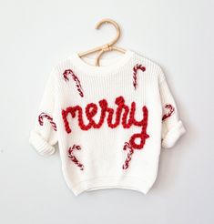 a white sweater with candy canes on it and the word merry written in red