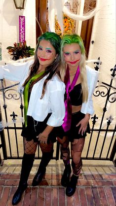 two women dressed in costumes standing next to each other on a brick floor near a gate